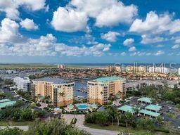 An aerial view shows multi-story apartment buildings near a marina with a blue sky above — 2090 MATECUMBE KEY ROAD UNIT 1705, PUNTA GORDA, FL