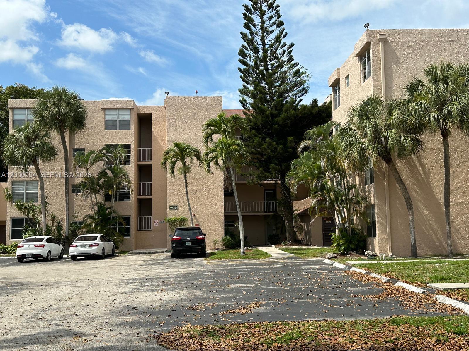 A multi-story apartment building with a parking lot and palm trees in front — 9410 Live Oak Pl # 305, Davie FL 33324, DAVIE, FL
