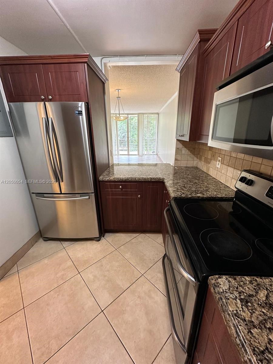 A kitchen features dark wood cabinets, granite countertops, stainless steel appliances, and tile flooring — 9410 Live Oak Pl # 305, Davie FL 33324, DAVIE, FL