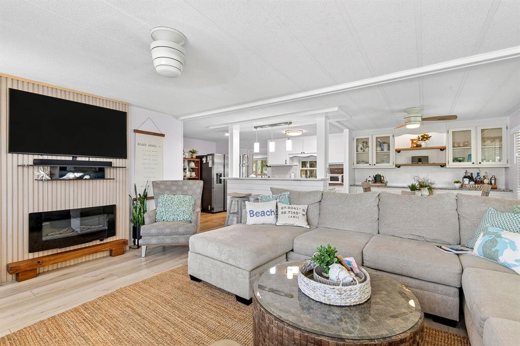 A living room features a sectional sofa, fireplace, wall-mounted television, and an open kitchen — 76 CABALLO WAY, BRADENTON, FL