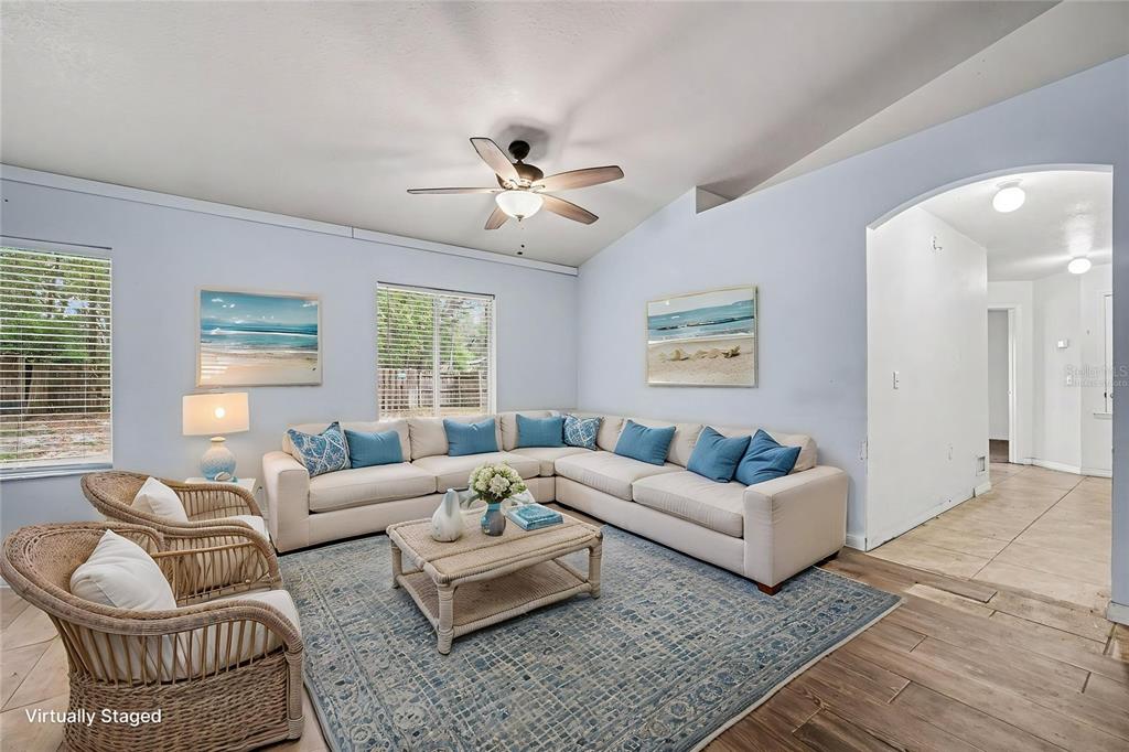 A living room features a large sectional sofa, two wicker chairs, and a blue rug — 890 DELAND AVENUE, ORANGE CITY, FL