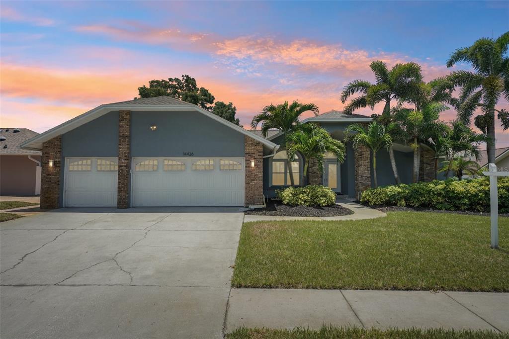 A front entryway features double glass doors with geometric designs and a brick-columned porch — 14426 MARK DRIVE, LARGO, FL