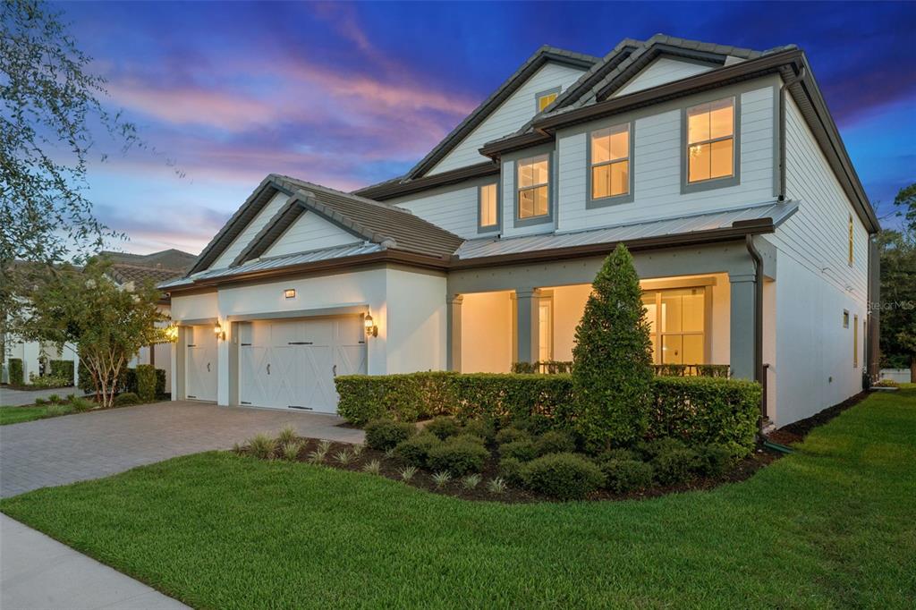 A two-story house with a white exterior, a two-car garage, and a covered front porch — 7606 WANDERING WAY, ORLANDO, FL