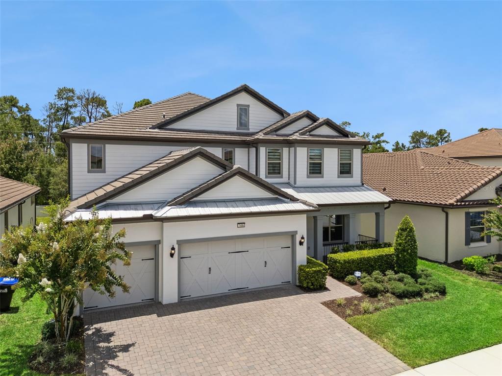 A two-story house with a three-car garage and a paved driveway under a blue sky — 7606 WANDERING WAY, ORLANDO, FL