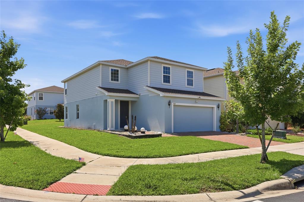 A two-story house with light blue siding, a two-car garage, and a front lawn — 4424 SILVER CREEK STREET, KISSIMMEE, FL
