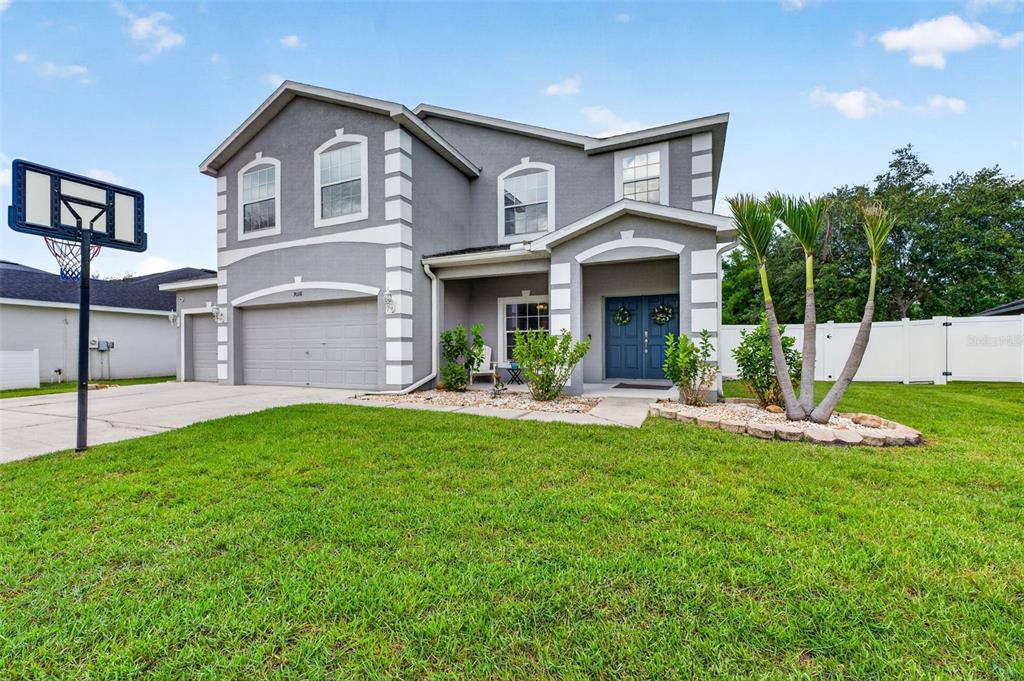 A two-story gray house with a three-car garage and a front lawn with a basketball hoop — 9018 N RIVER ROAD, TAMPA, FL