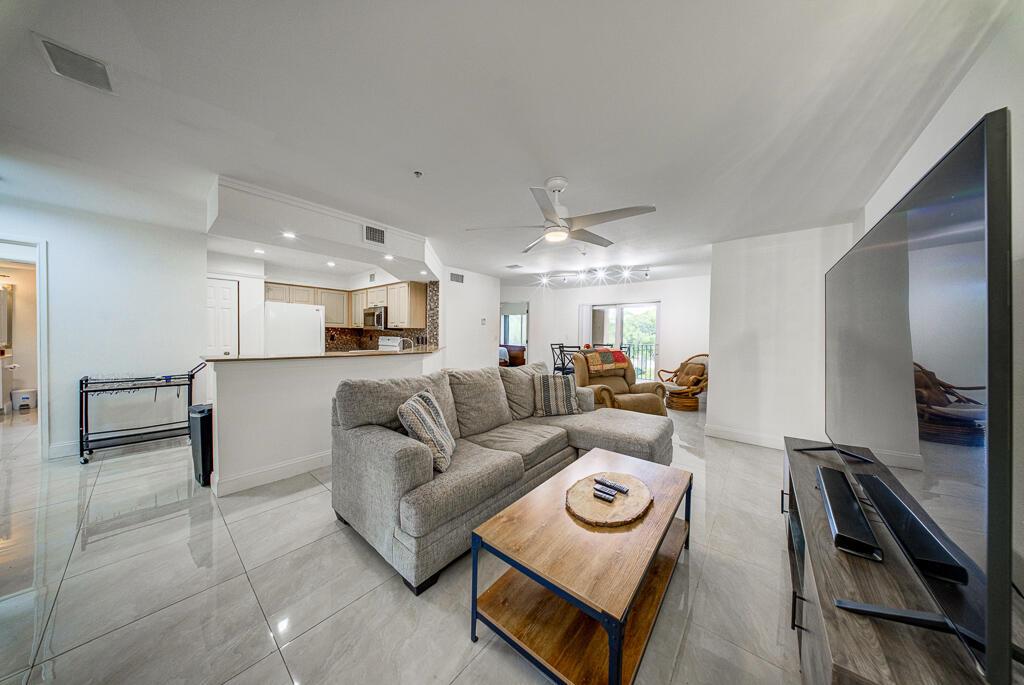 A living room with light tile floors, a gray sectional sofa, and an open kitchen — 500 Scotia Drive # 302, Hypoluxo FL 33462, HYPOLUXO, FL