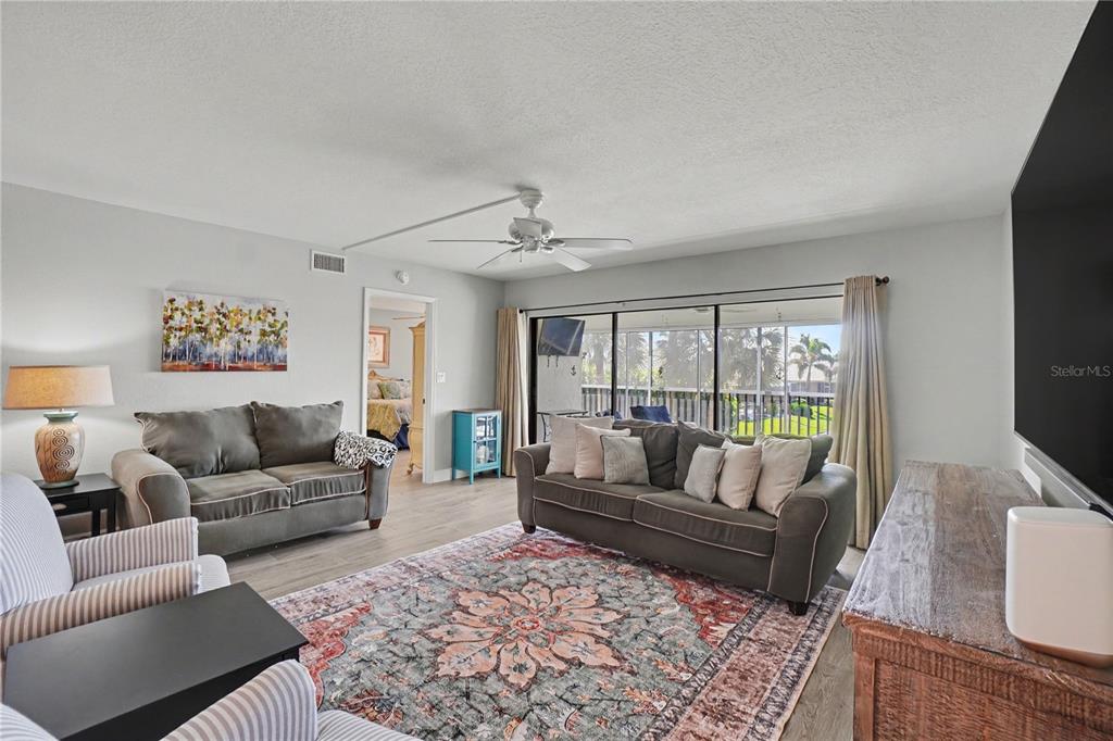 A living room features two gray sofas, a patterned area rug, and sliding glass doors — 601 SHREVE STREET UNIT 54B, PUNTA GORDA, FL