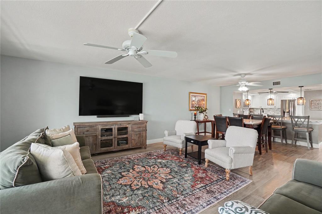A living room with a large television, area rug, and an open kitchen in back — 601 SHREVE STREET UNIT 54B, PUNTA GORDA, FL