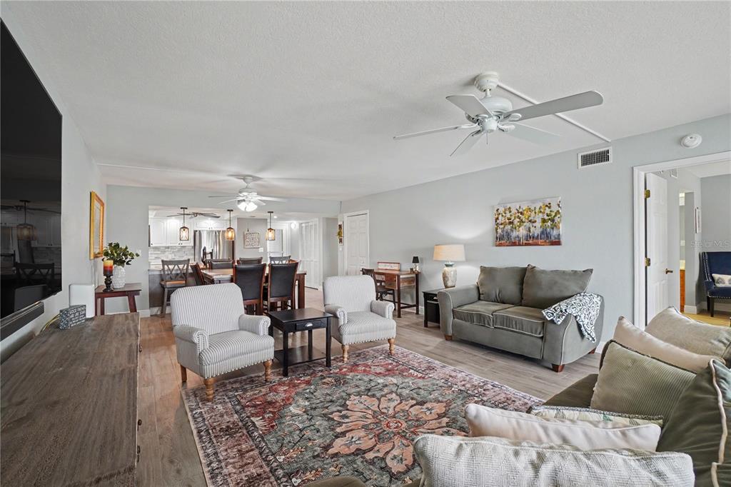 An open-concept living and dining area features light wood flooring, a ceiling fan, and furniture — 601 SHREVE STREET UNIT 54B, PUNTA GORDA, FL