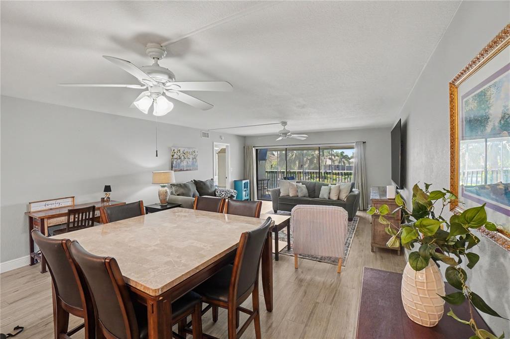 An open-concept living and dining area features a stone-topped table, ceiling fans, and sliding doors — 601 SHREVE STREET UNIT 54B, PUNTA GORDA, FL