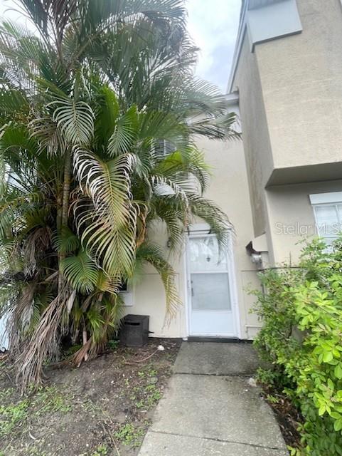 A concrete walkway leads to the white front door of a multi-story townhouse with palm trees — 6600 121ST AVENUE UNIT 6, LARGO, FL