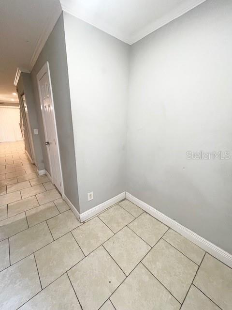 A hallway with light gray walls and beige tile flooring leads to a closed door — 6600 121ST AVENUE UNIT 6, LARGO, FL