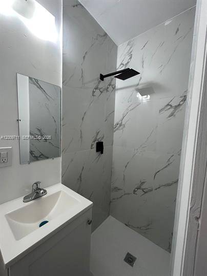 A small bathroom features a white vanity, a mirror, and a walk-in shower with marble-patterned tiles — 7714 NW 5th Ave, Miami FL 33150, MIAMI, FL