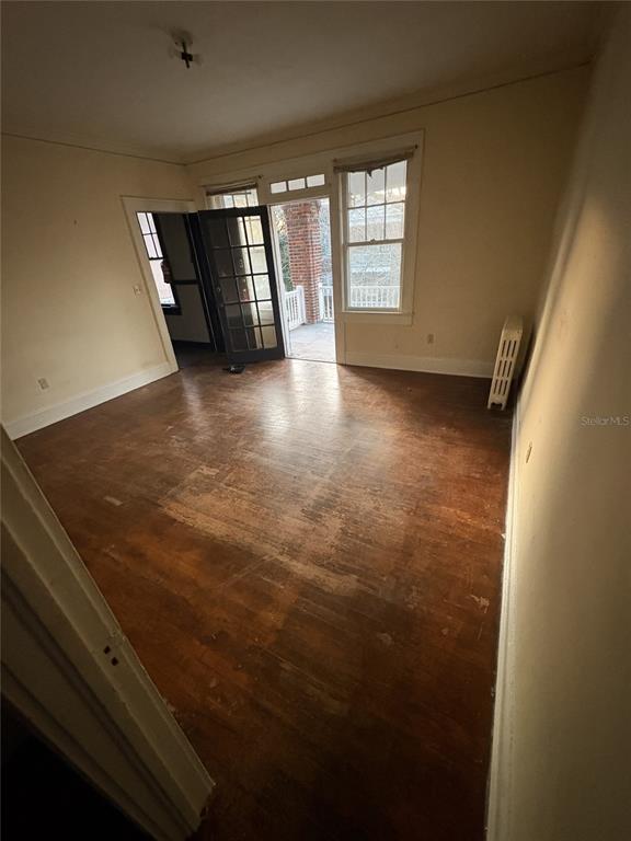 An empty room with hardwood floors, a radiator, and a glass door leading to a porch — 1975 VINEVILLE AVENUE UNIT F3, MACON, GA