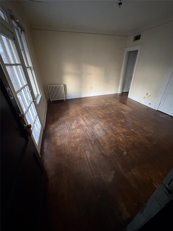 An empty room features hardwood floors, a radiator, and a glass-paneled door — 1975 VINEVILLE AVENUE UNIT F3, MACON, GA
