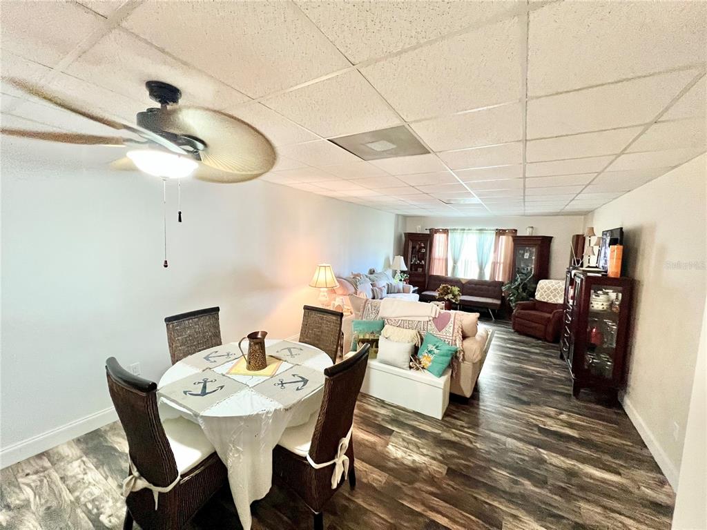 A dining area with a round table transitions into a living room with wood-look flooring — 3116 HARBOR BOULEVARD UNIT 1B, PORT CHARLOTTE, FL