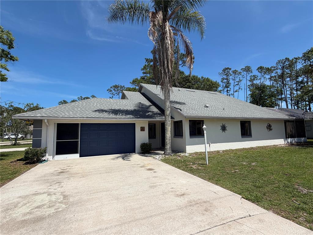 A single-story house with a blue garage door, a concrete driveway, and a tall palm tree — 12 WELLWOOD LANE UNIT A & B, PALM COAST, FL