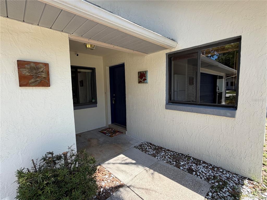 The exterior view shows a white stucco house with a blue front door and windows — 12 WELLWOOD LANE UNIT A & B, PALM COAST, FL