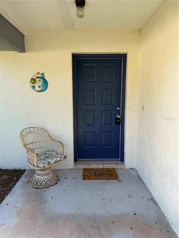 A blue front door with a wicker chair and a welcome mat on a porch — 12 WELLWOOD LANE UNIT A & B, PALM COAST, FL