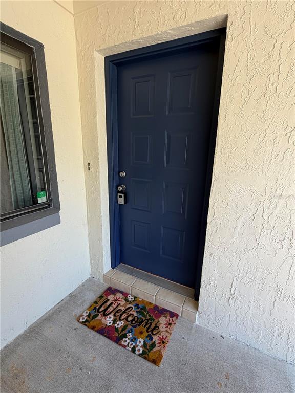 A blue front door with a lockbox sits on a concrete porch with a doormat — 12 WELLWOOD LANE UNIT A & B, PALM COAST, FL