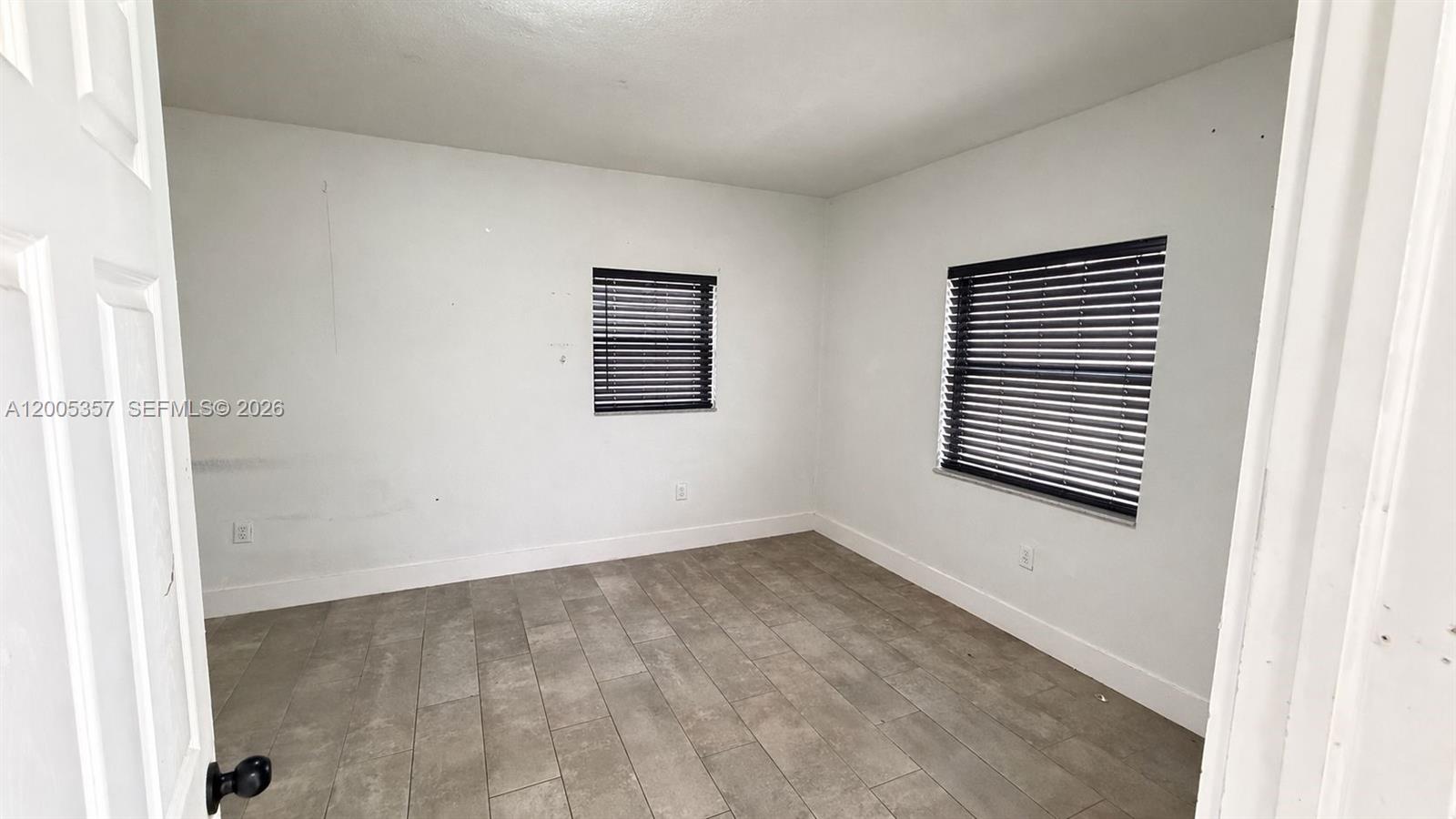 An empty room features white walls, tile flooring, and two windows with dark blinds — 301 NW 37th St # A, Miami FL 33127, MIAMI, FL