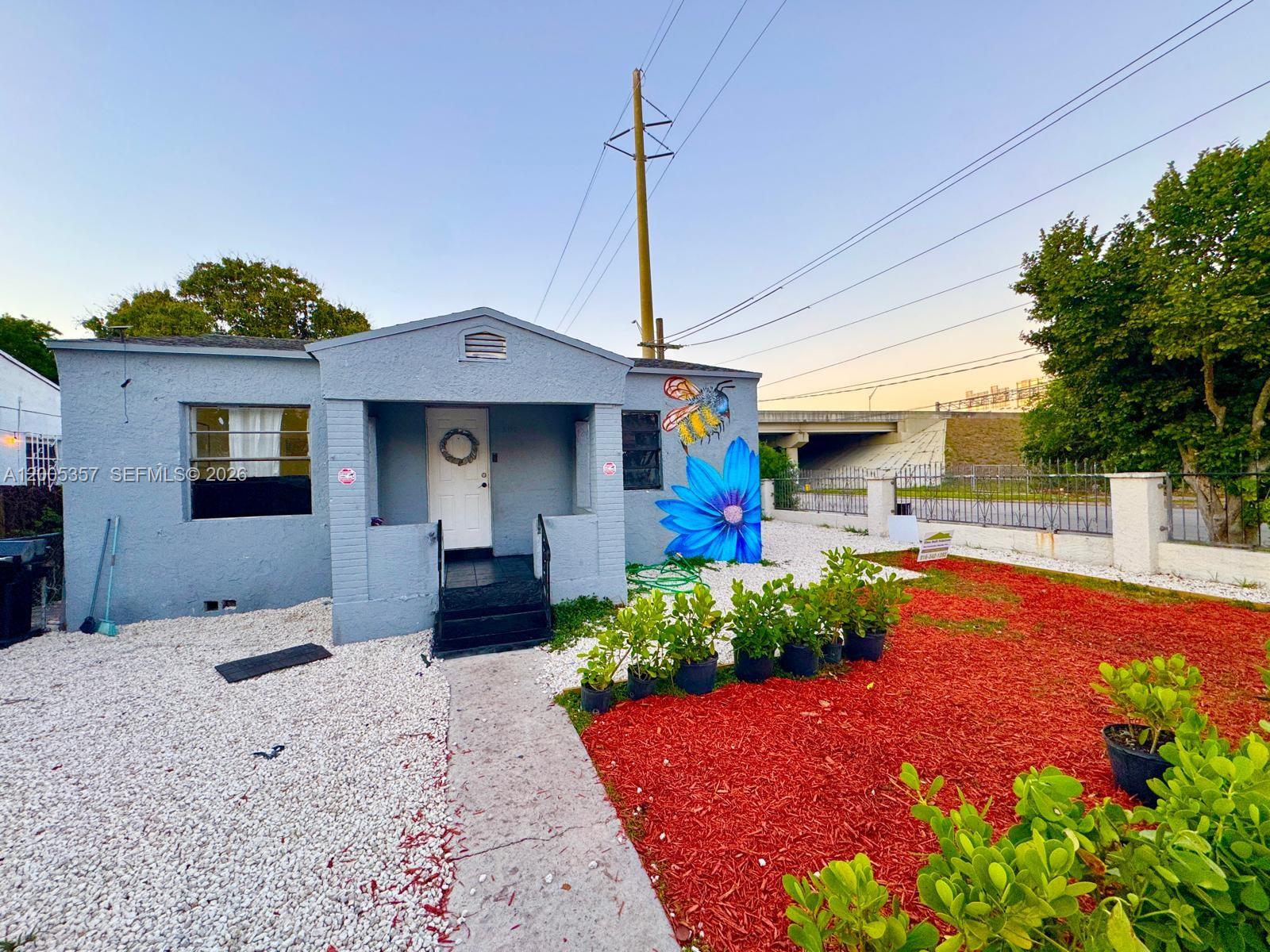 A light blue house features a bee and flower mural, white gravel, and red mulch — 301 NW 37th St # A, Miami FL 33127, MIAMI, FL