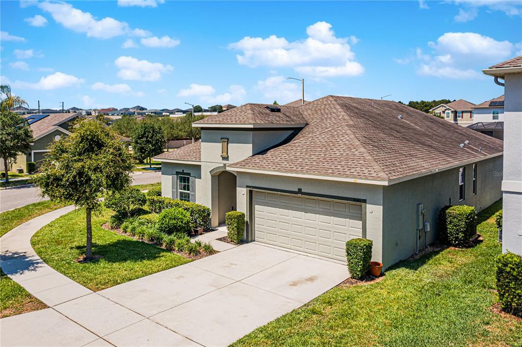 A single-story suburban house with a tan stucco exterior, a two-car garage, and a driveway — 3040 SANDERLING STREET, HAINES CITY, FL
