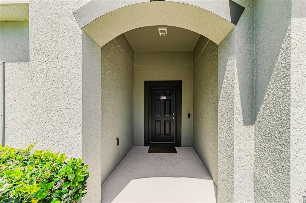 A recessed entryway features a dark front door with a small number one on the wall — 3040 SANDERLING STREET, HAINES CITY, FL