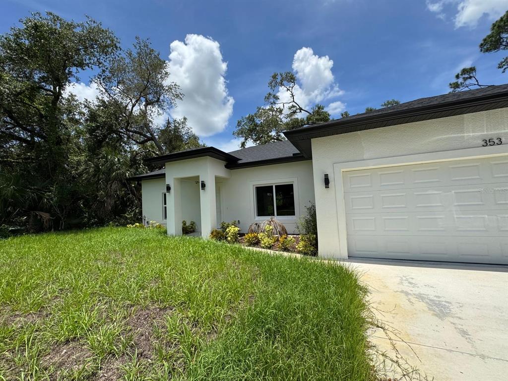 A white single-story house with a dark roof and a concrete driveway under a blue sky — 353 WARRINGTON BOULEVARD, PORT CHARLOTTE, FL