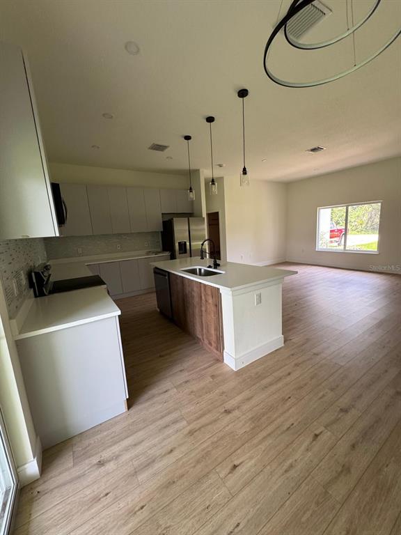 A modern kitchen features white cabinets, a wood-accented island, and light wood-look flooring — 353 WARRINGTON BOULEVARD, PORT CHARLOTTE, FL
