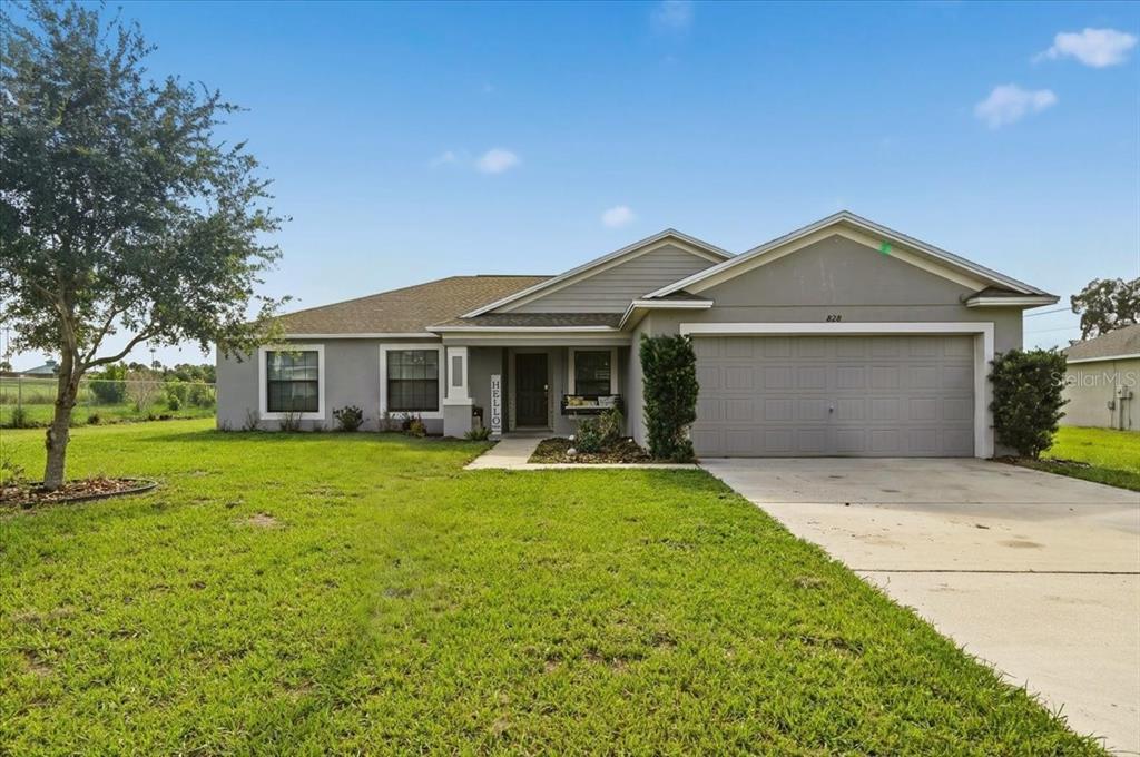 A single-story house with a gray exterior, a two-car garage, and a front lawn — 828 ULMER ROAD, FROSTPROOF, FL