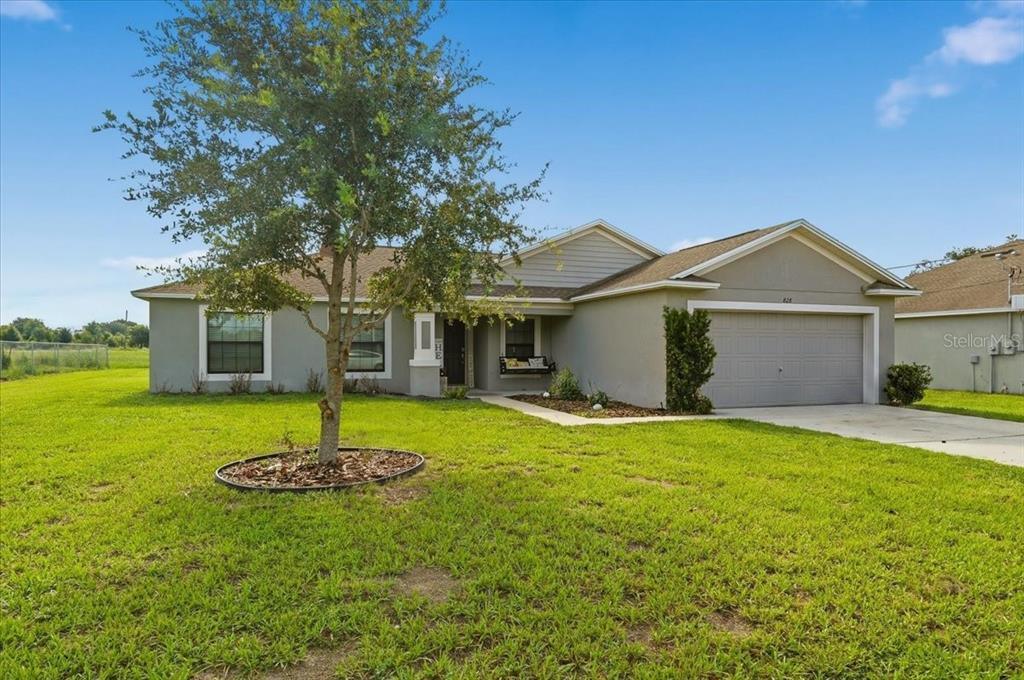 A single-story house with a gray exterior, a two-car garage, and a front yard tree — 828 ULMER ROAD, FROSTPROOF, FL