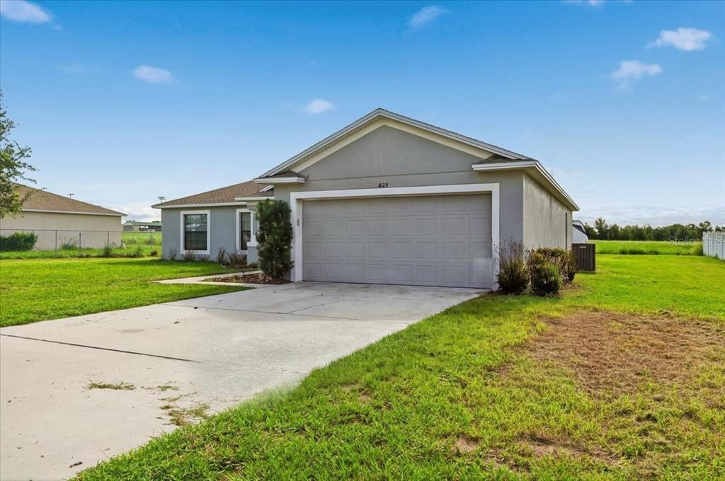 A single-story house with a gray stucco exterior, a two-car garage, and a concrete driveway — 828 ULMER ROAD, FROSTPROOF, FL