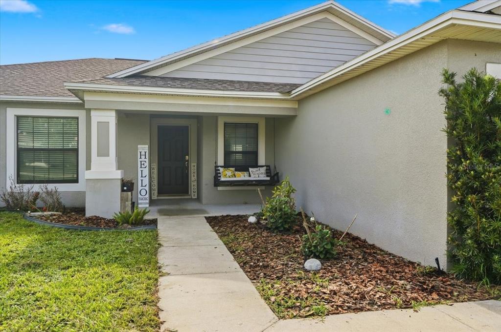 A concrete walkway leads to the covered front porch of a single-story suburban home — 828 ULMER ROAD, FROSTPROOF, FL