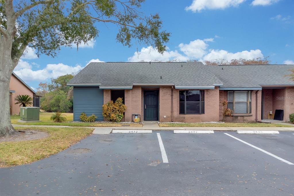A single-story brick townhouse with a dark front door and two parking spaces in front — 2432 KING OAK COURT, ST CLOUD, FL