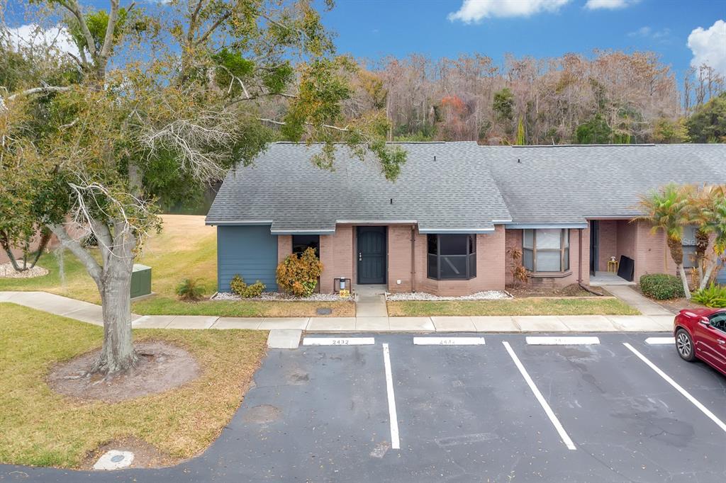 An exterior view of a single-story brick townhouse with a parking lot in front — 2432 KING OAK COURT, ST CLOUD, FL