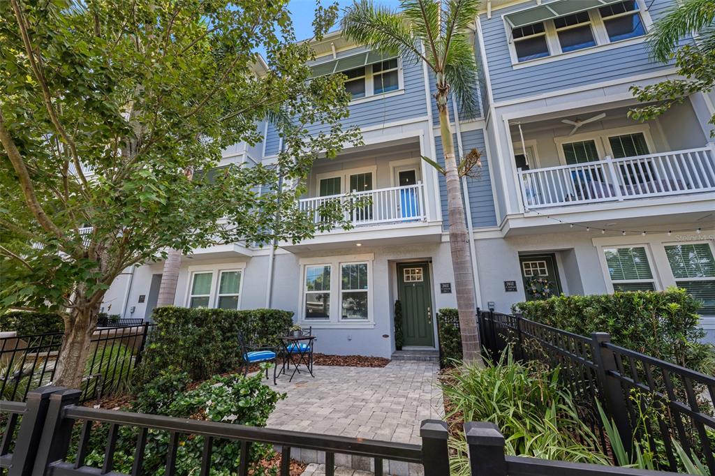 A three-story townhouse exterior features a paved front patio, a green door, and balconies — 2602 W CLEVELAND STREET UNIT 3, TAMPA, FL