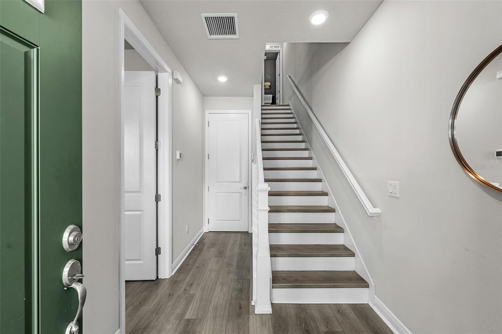An entryway features wood-look flooring, a white staircase, and a green front door — 2602 W CLEVELAND STREET UNIT 3, TAMPA, FL