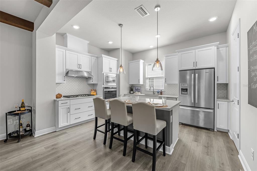 A modern kitchen features white cabinetry, stainless steel appliances, a gray island, and wood flooring — 2602 W CLEVELAND STREET UNIT 3, TAMPA, FL