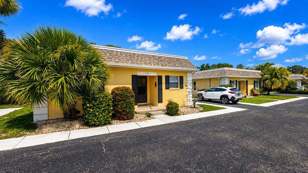 A yellow single-story building with a shingled roof and a white SUV parked nearby — 2405 ASPINWALL STREET UNIT 2405, SARASOTA, FL