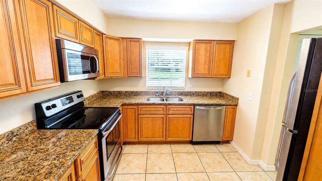 A kitchen with wood cabinets, granite countertops, stainless steel appliances, and tile flooring — 2405 ASPINWALL STREET UNIT 2405, SARASOTA, FL