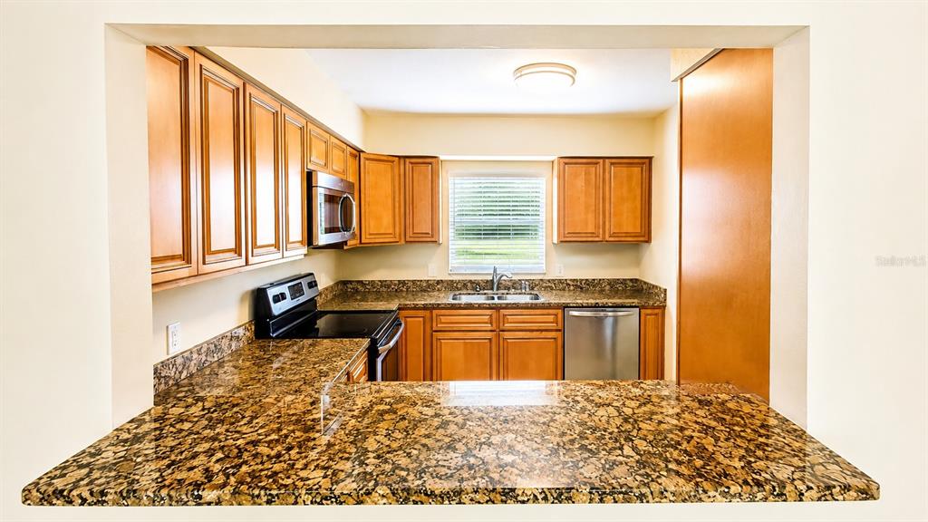 A kitchen features wood cabinets, granite countertops, and stainless steel appliances — 2405 ASPINWALL STREET UNIT 2405, SARASOTA, FL