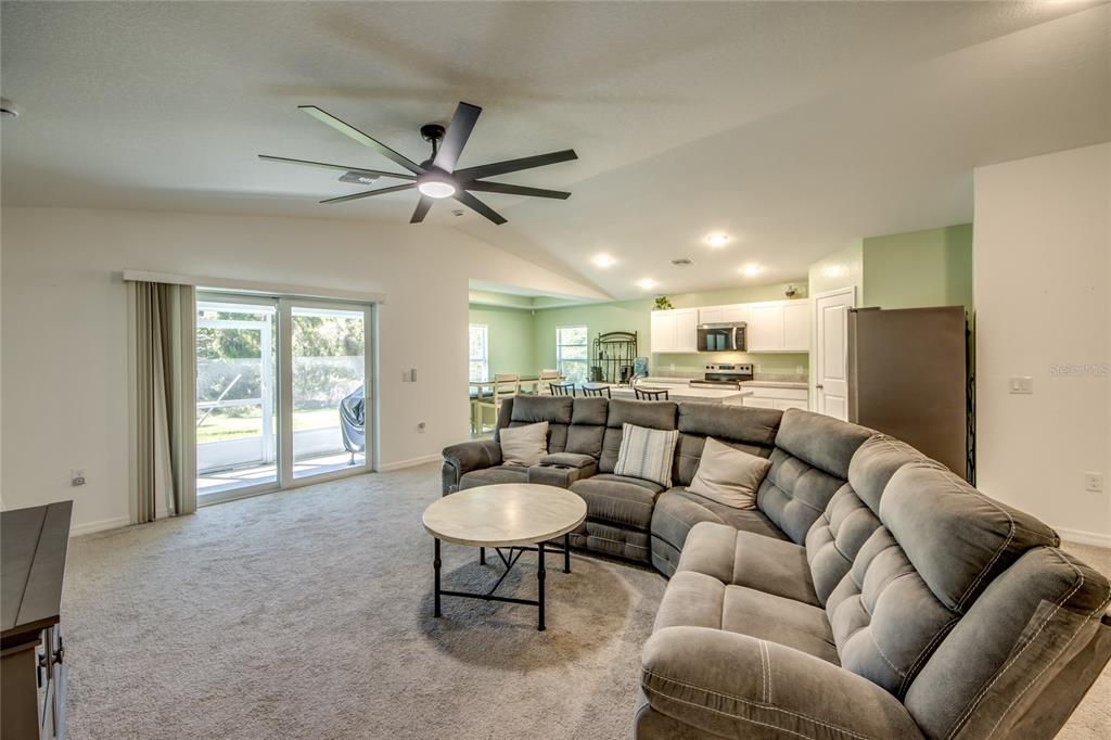 A living room with a grey sectional sofa, a round coffee table, and an open kitchen — 16069 EDINA AVENUE, PORT CHARLOTTE, FL