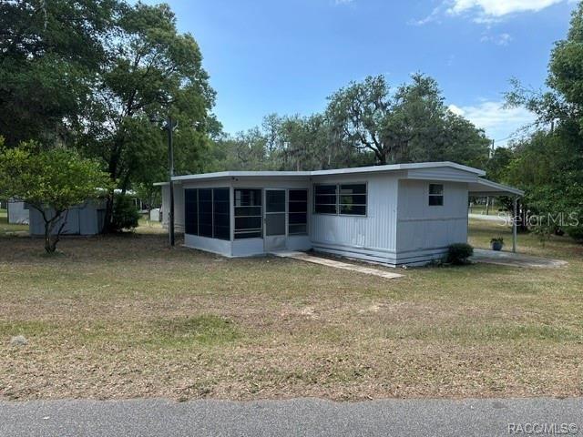 A single-story mobile home with a screened-in porch sits on a grassy lot with trees — 4546 N TUMBLEWEED TRAIL, HERNANDO, FL