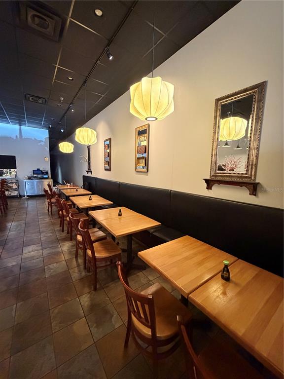 A restaurant dining area features wooden tables, black booth seating, and hanging pendant lights — 4742 FLORIDA AVE SOUTH, LAKELAND, FL
