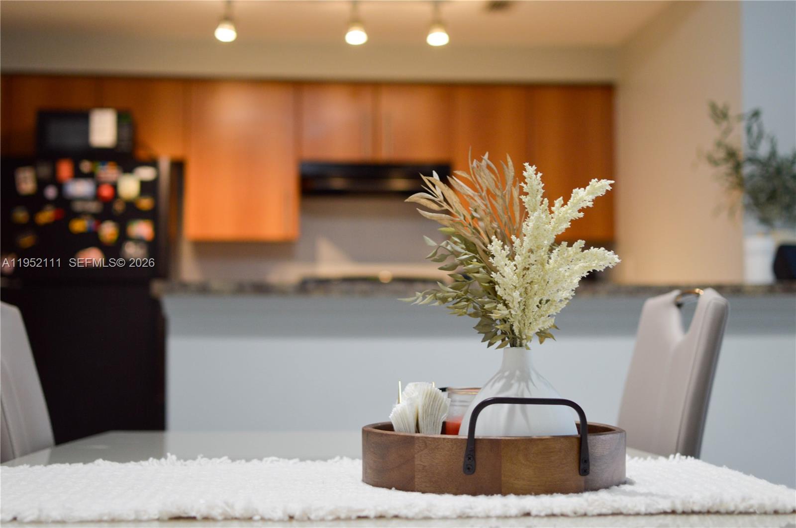 A dining table centerpiece sits in the foreground with a kitchen visible in the background — 5840 W Sample Rd # 305, Coral Springs FL 33067, CORAL SPRINGS, FL