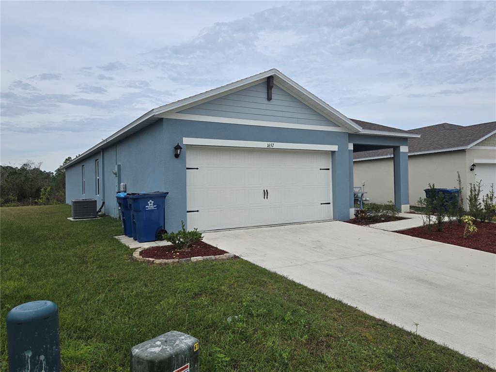 A blue single-story house with a two-car garage and a concrete driveway — 1657 ROSYDALE CIRCLE, DAVENPORT, FL