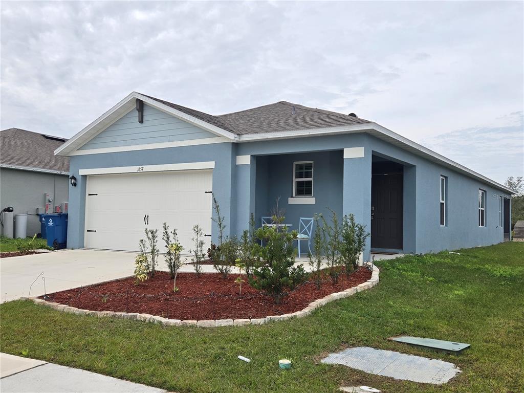 A blue single-story house with a two-car garage and a small front porch — 1657 ROSYDALE CIRCLE, DAVENPORT, FL