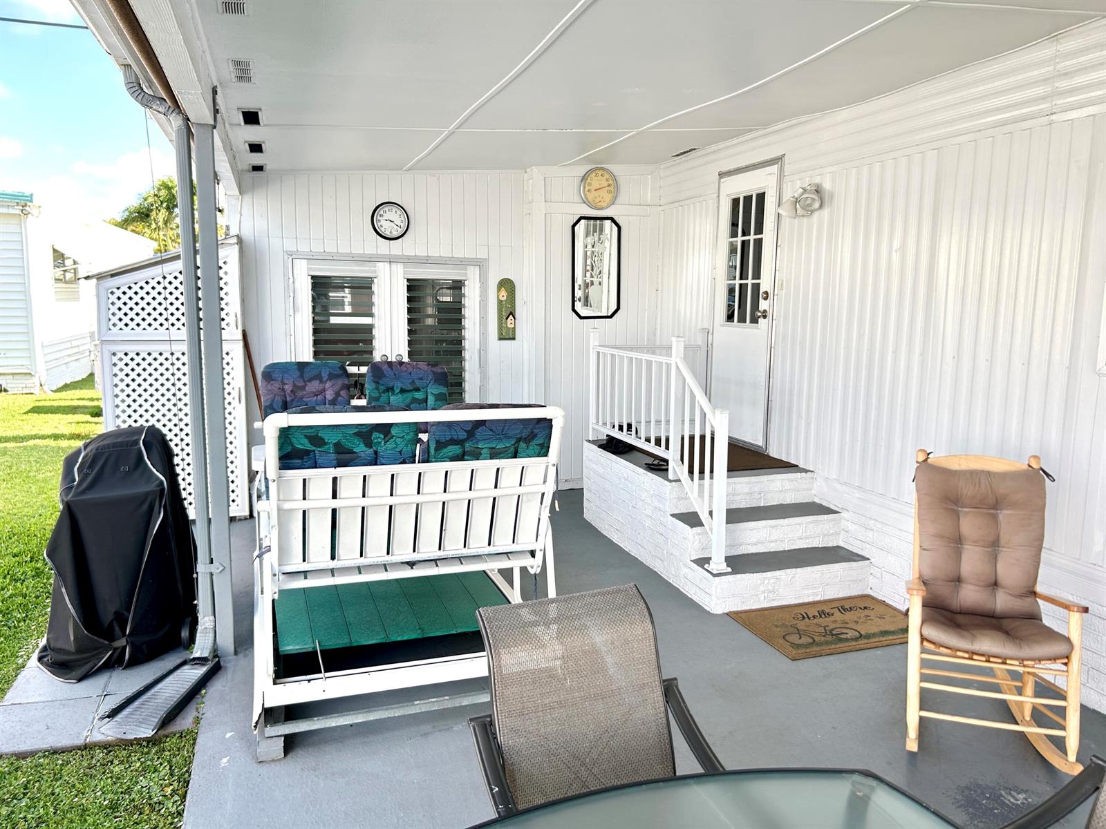 A covered patio features a white porch swing, a rocking chair, and steps to a door — 3233 State Street, Hollywood FL 33021, HOLLYWOOD, FL